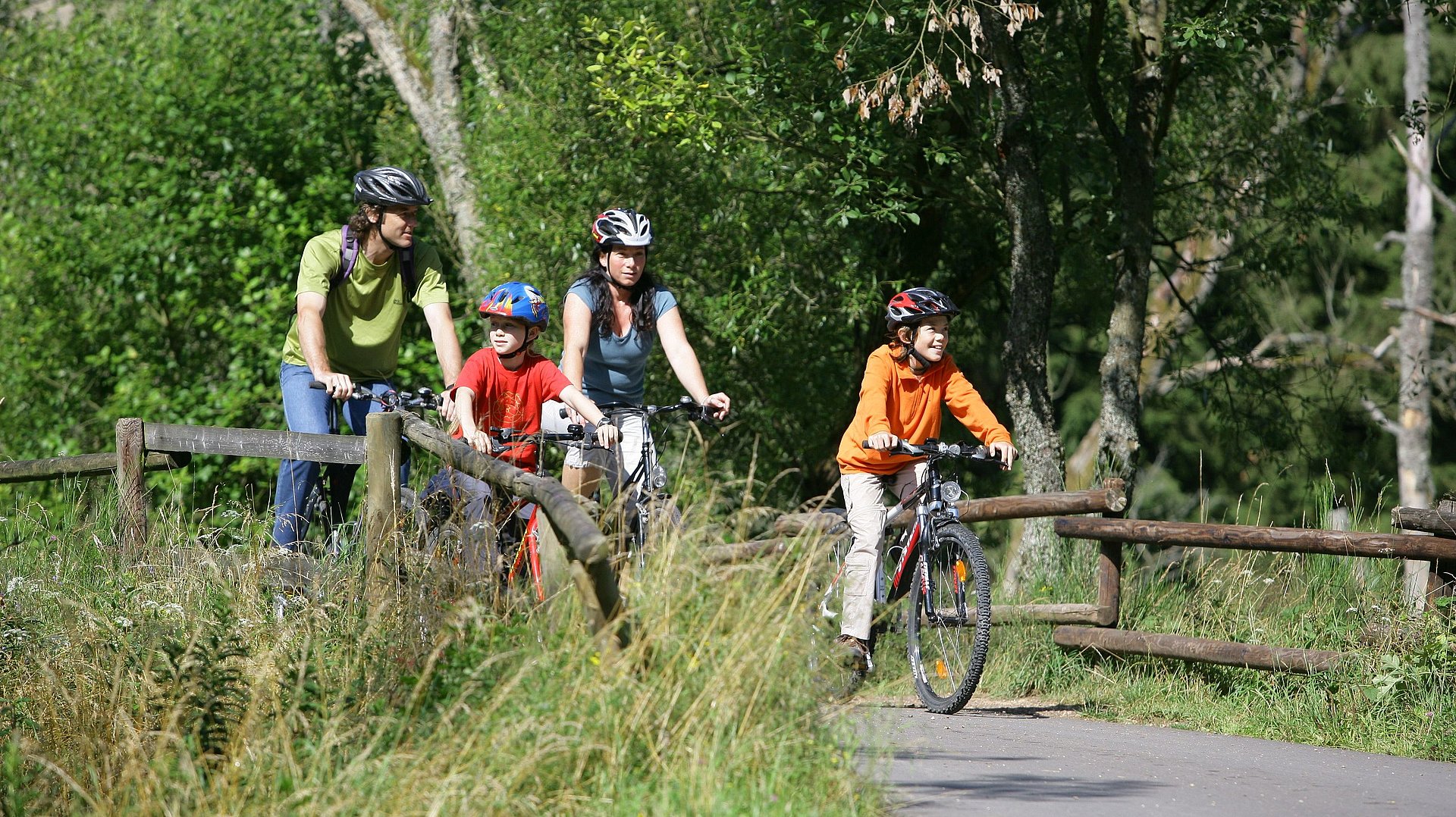 Eine Familie fährt mit den Rädern auf einem Radweg.