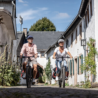 Radfahrer sind im historischen Burgort Kronenburg unterwegs