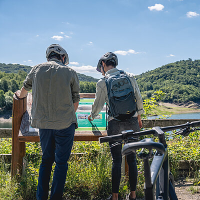 Zwei Radfahrer informieren sich unterwegs an einer Infotafel