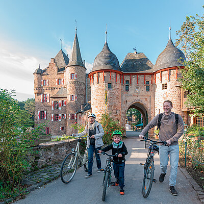 Eltern und ein Kind mit ihren Rädern vor der Burg Satzvey