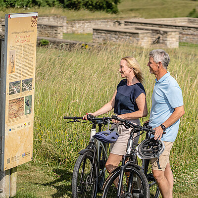 Zwei Radfahrer informieren sich im Archäologischen Landschaftspark