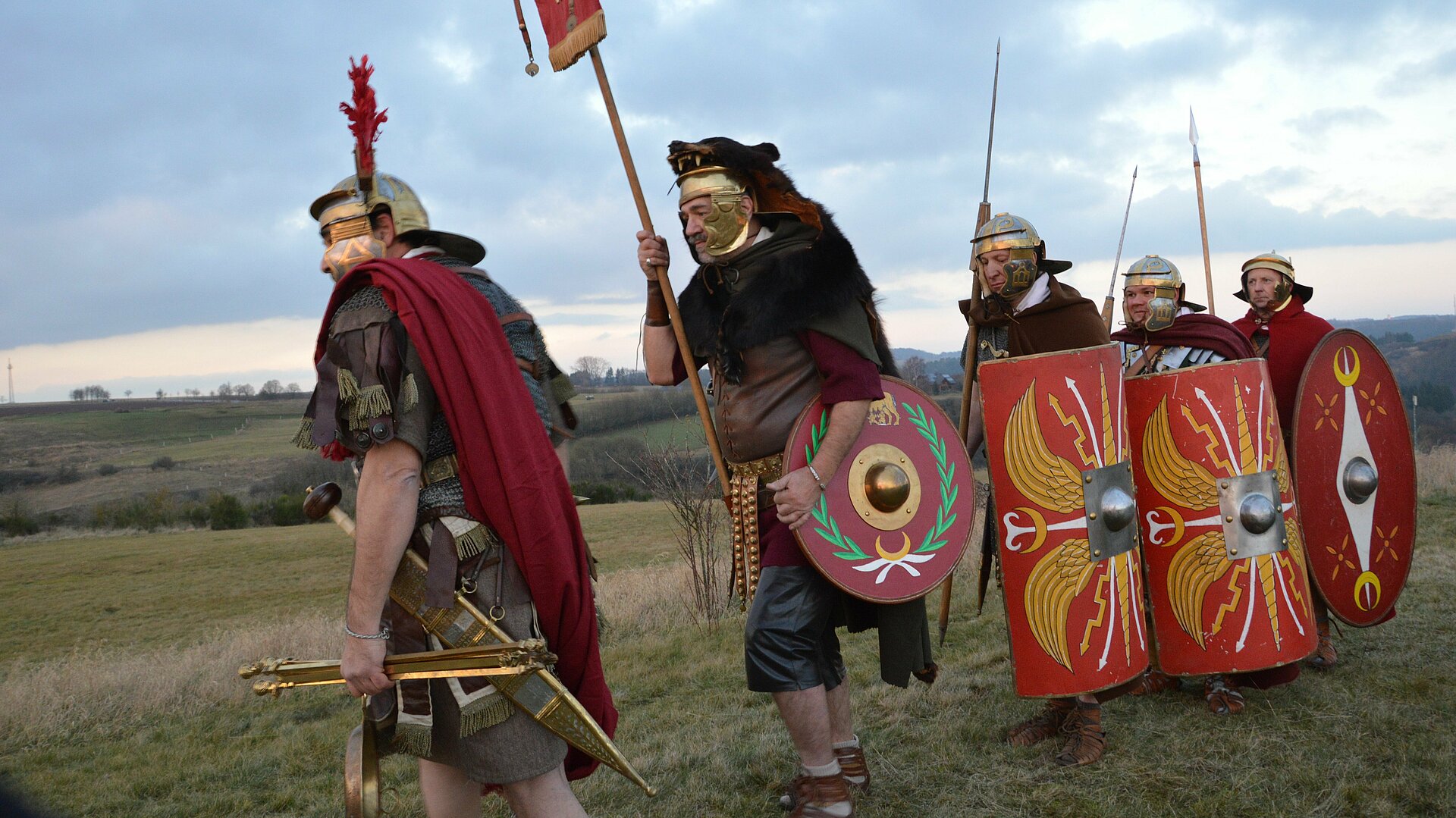 Fünf verkleidete Römer marschieren über ein Feld