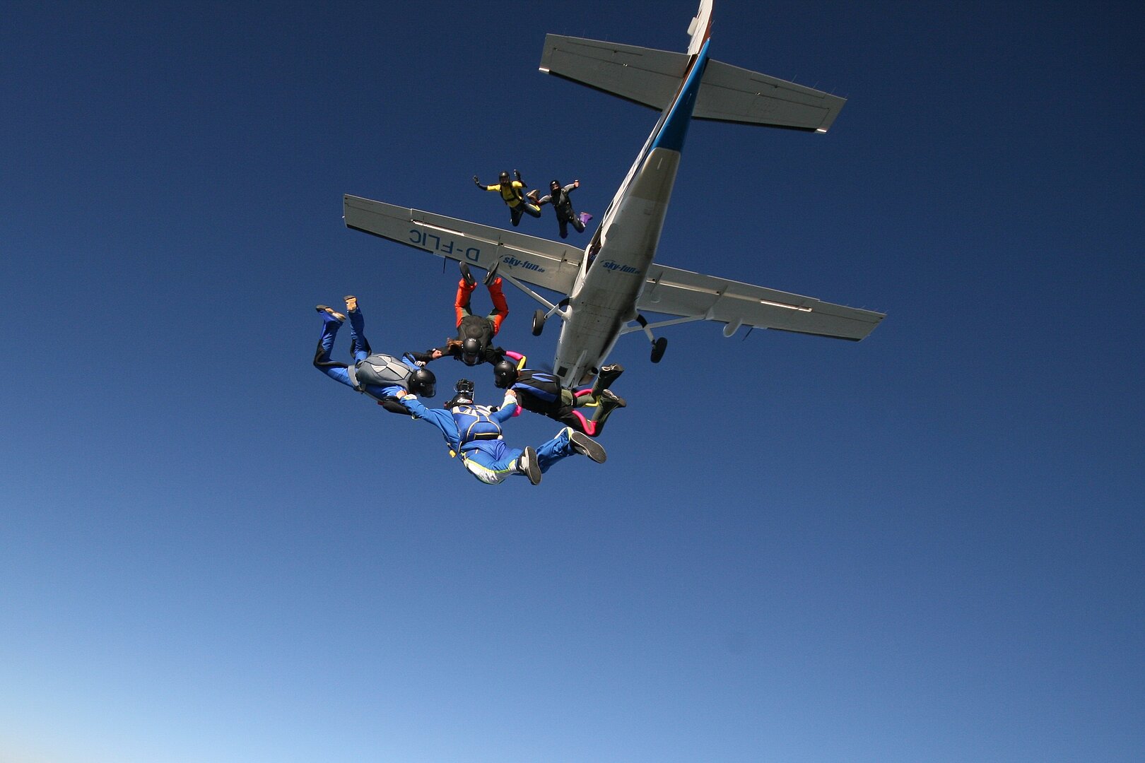 Fallschirmspringer aus Flugzeug im blauen Himmel