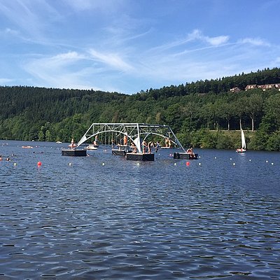 Auf dem Kronenburger See schwimmt ein Kletterturm mit Menschen