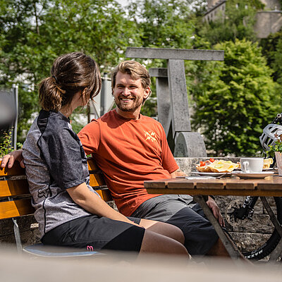 Ein Paar sitzt beim Radlerfrühstück auf einer Terasse