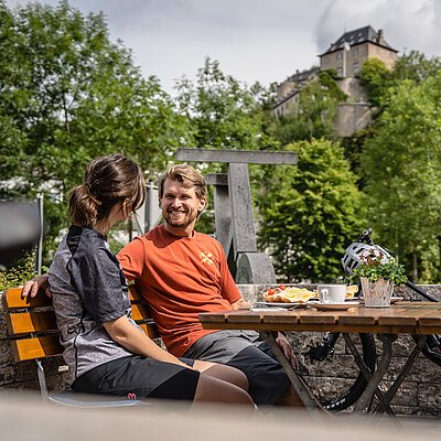 Ein Paar sitzt beim Radlerfrühstück auf einer Terasse