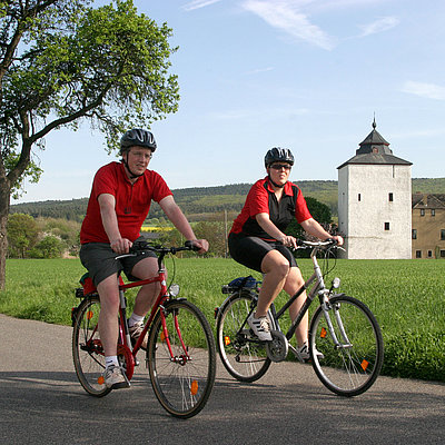 Zwei Radfahrer fahren auf dem Erftradweg mit Burg im Hintergrund