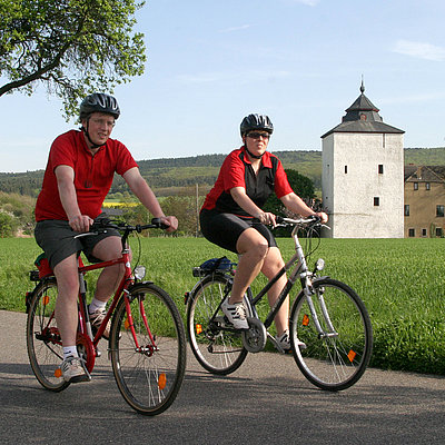 Zwei Radfahrer fahren auf dem Erftradweg mit Burg im Hintergrund