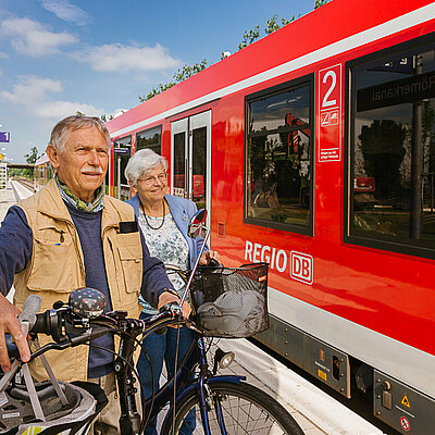 Ein Paar steht mit den Rädern am Bahnsteig während der Zug einfährt
