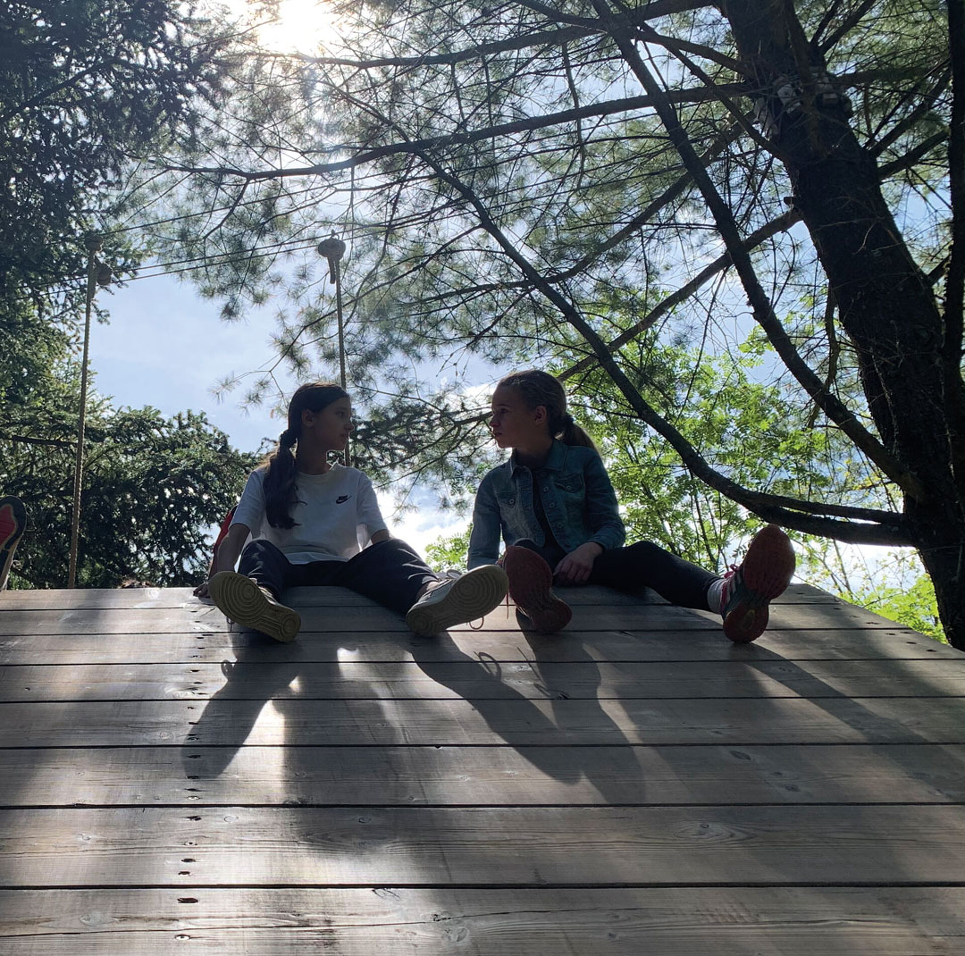 zwei Mädchen sitzen auf einer Holzwand