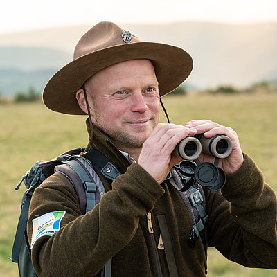 Ranger Sasche beobachtet mit seinem Fernglas die Tierwelt im Nationalpark Eifel