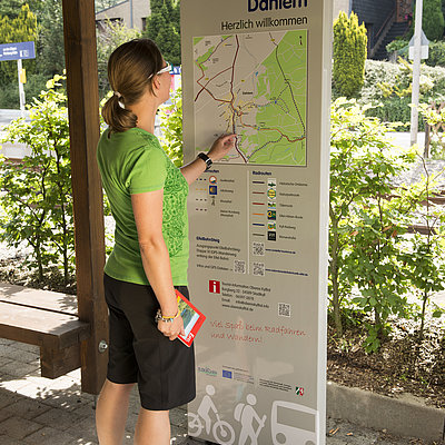 Wanderer orientiert sich an einer Informationstafel auf dem Bahnsteig