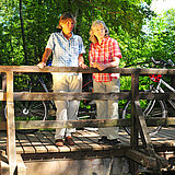 Ein Paar steht mit Rädern auf der Brücke an der Quelle der Erft.